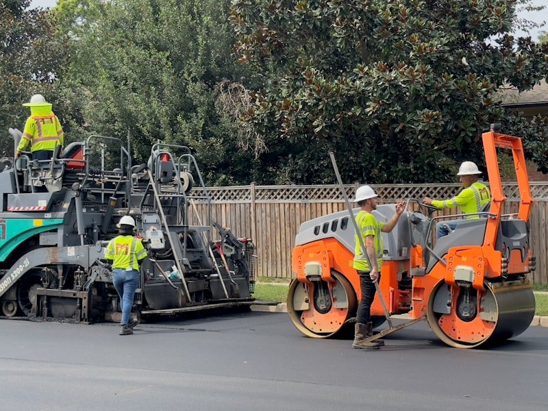 Crew placing fresh hot-mix asphalt on a new driveway installation