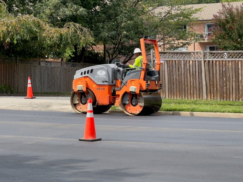 Worker finishing the widened edge of an asphalt driveway approach